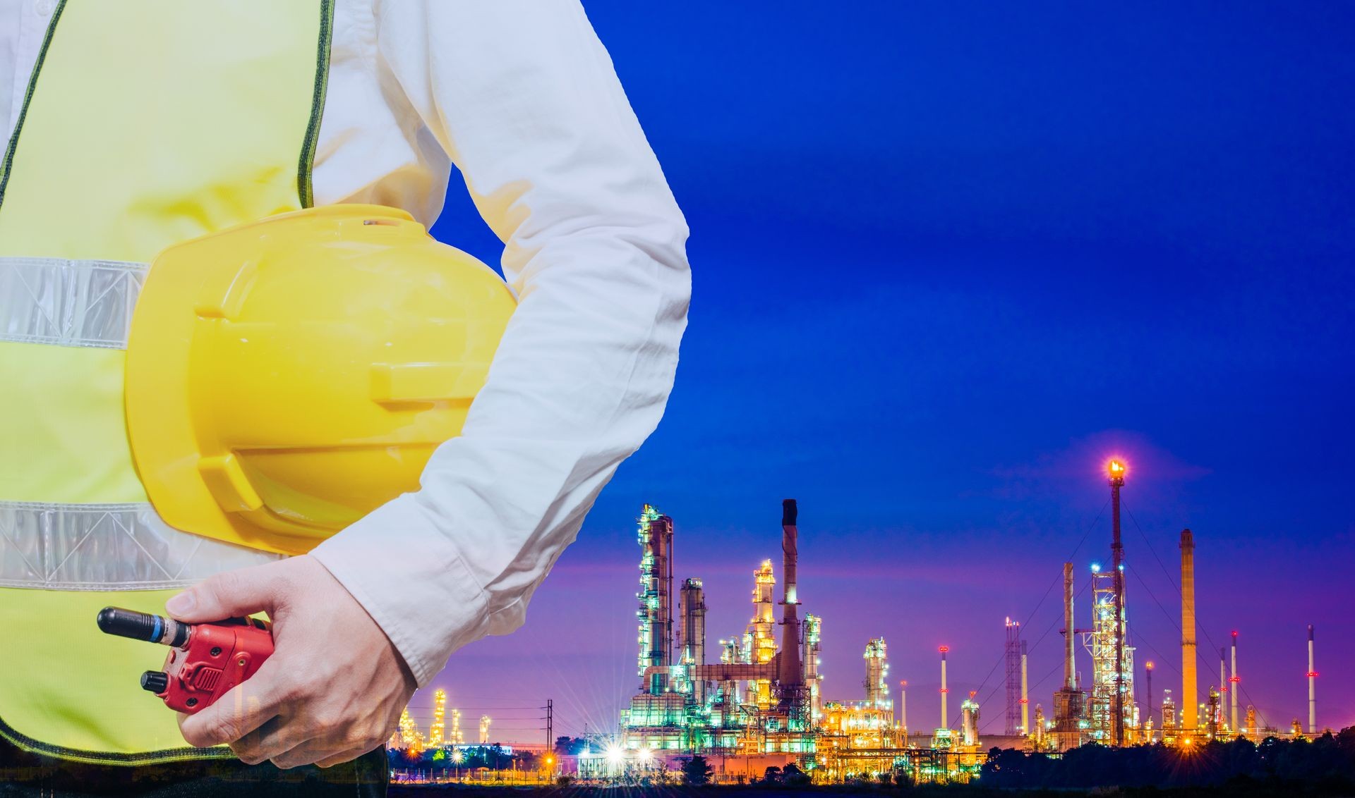 engineering man standing with white safety helmet against oil refinery in petrochemical Aerial view oil refinery night during twilight,Industrial zone,Energy power station background.